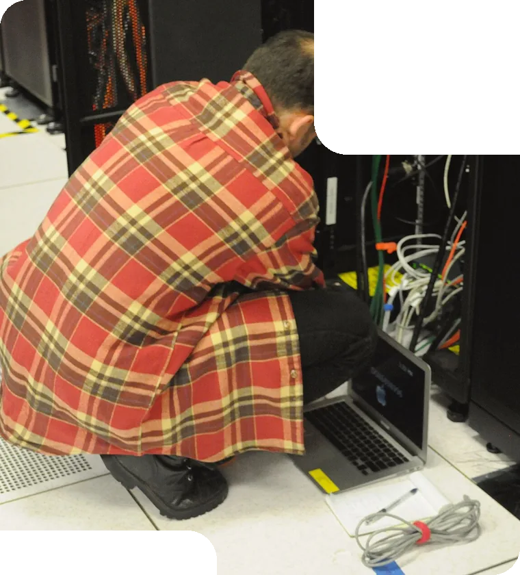 Engineer at a server rack with a laptop